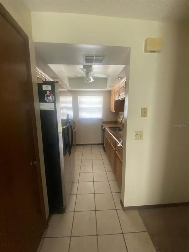 kitchen with visible vents, light tile patterned floors, a sink, stainless steel fridge, and a tray ceiling