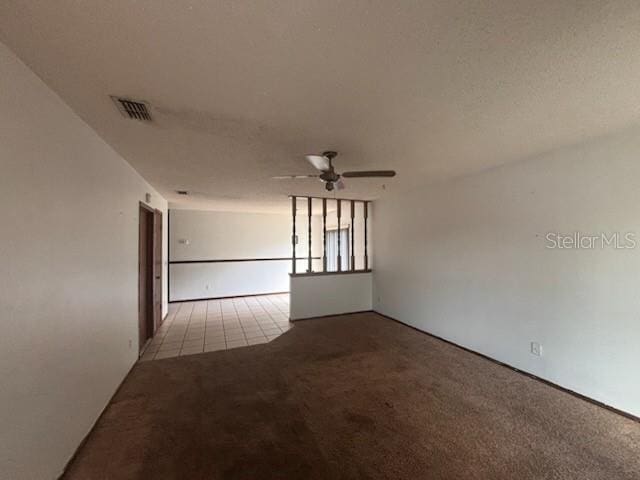 carpeted empty room with ceiling fan and visible vents