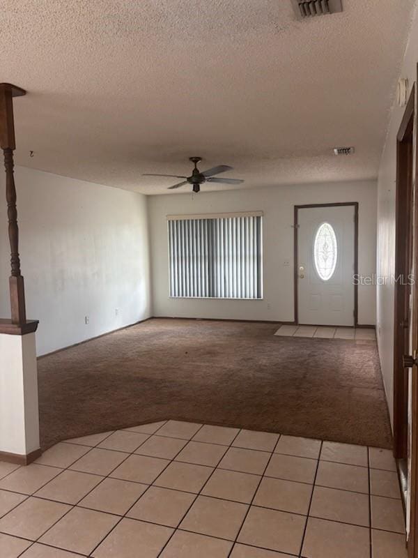foyer with a textured ceiling, light colored carpet, and ceiling fan
