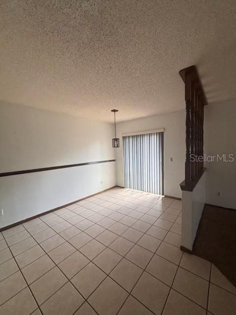 empty room with a textured ceiling and light tile patterned floors