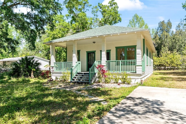 bungalow-style home with a shingled roof, a front lawn, and a porch