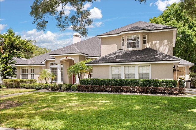 3637 Rothbury Dr, Belle Isle, FL 32812 - view of front of home with a chimney, a shingled roof, stucco siding, and a front yard