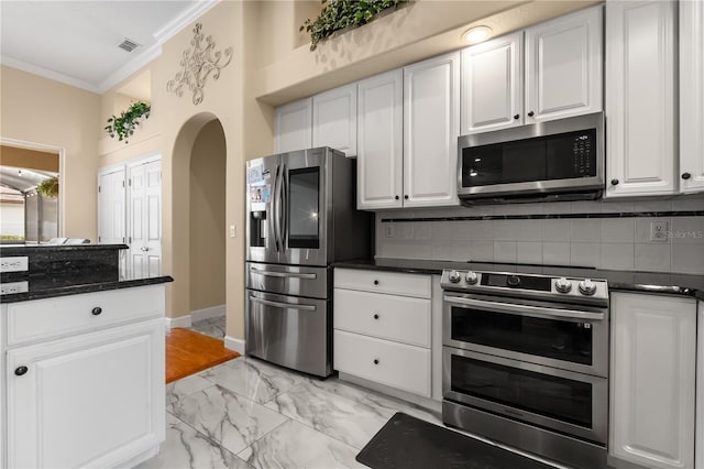 3637 Rothbury Dr, Belle Isle, FL 32812 - kitchen featuring appliances with stainless steel finishes, marble finish floor, white cabinetry, tasteful backsplash, and ornamental molding
