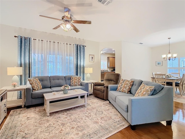 501 Heartwell Dr, Poinciana, FL 34759 - living area featuring arched walkways, ceiling fan with notable chandelier, light wood-style floors, and visible vents
