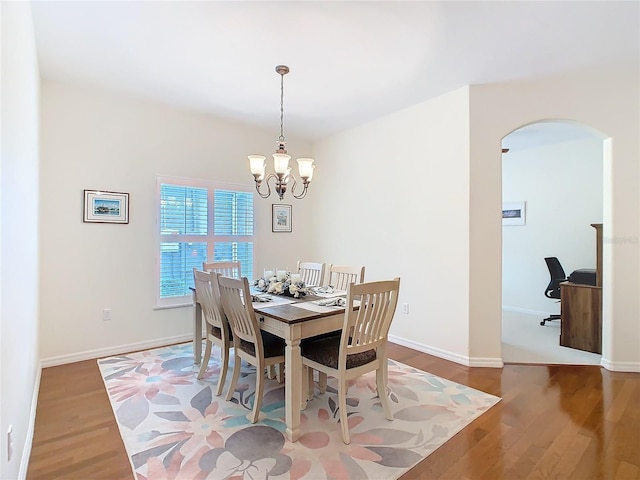 501 Heartwell Dr, Poinciana, FL 34759 - dining space with baseboards, a notable chandelier, wood finished floors, and arched walkways