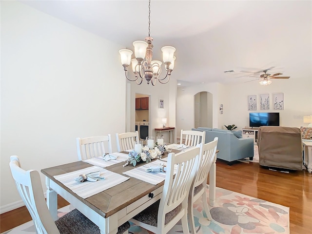501 Heartwell Dr, Poinciana, FL 34759 - dining area with arched walkways, visible vents, wood finished floors, and ceiling fan with notable chandelier