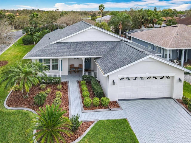 501 Heartwell Dr, Poinciana, FL 34759 - view of front of home with decorative driveway, a garage, stucco siding, a shingled roof, and a porch