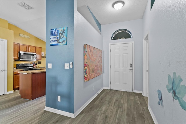 323 Azincourt Ln, Kissimmee, FL 34759 - entrance foyer with baseboards, visible vents, wood finished floors, and vaulted ceiling