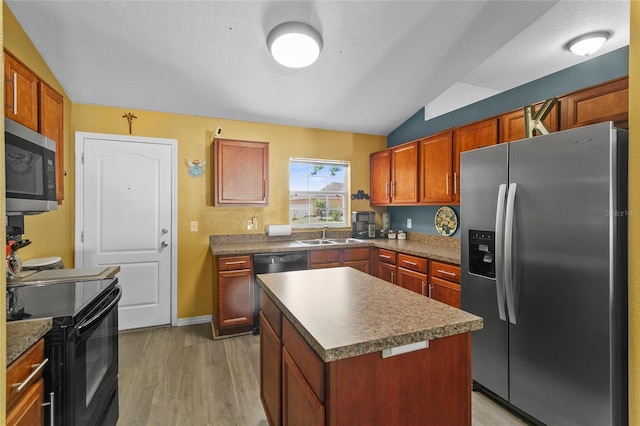 323 Azincourt Ln, Kissimmee, FL 34759 - kitchen with lofted ceiling, a kitchen island, a sink, light wood-style flooring, and black appliances