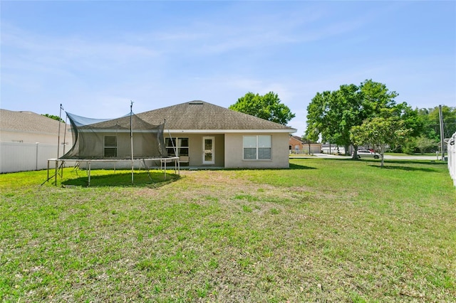 323 Azincourt Ln, Kissimmee, FL 34759 - back of property featuring a yard, stucco siding, fence, and a trampoline
