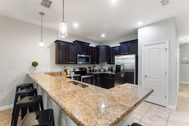 kitchen with a peninsula, a sink, appliances with stainless steel finishes, and visible vents