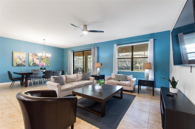 living area with ceiling fan with notable chandelier, baseboards, and light tile patterned floors