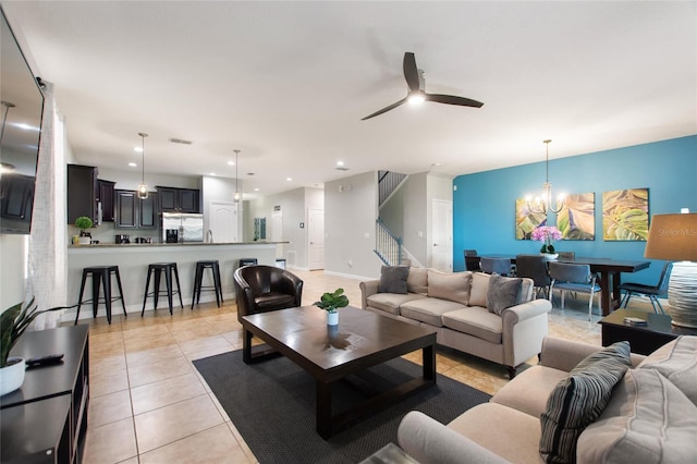 living area featuring light tile patterned flooring, stairway, ceiling fan with notable chandelier, visible vents, and recessed lighting