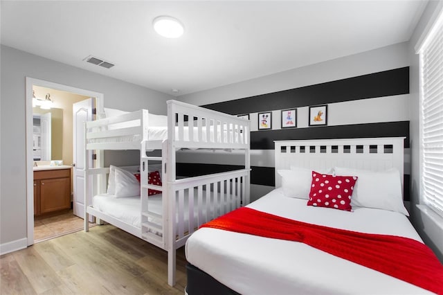 bedroom featuring ensuite bath, light wood-style floors, and visible vents