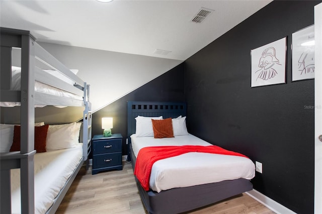bedroom with baseboards, visible vents, and wood finished floors