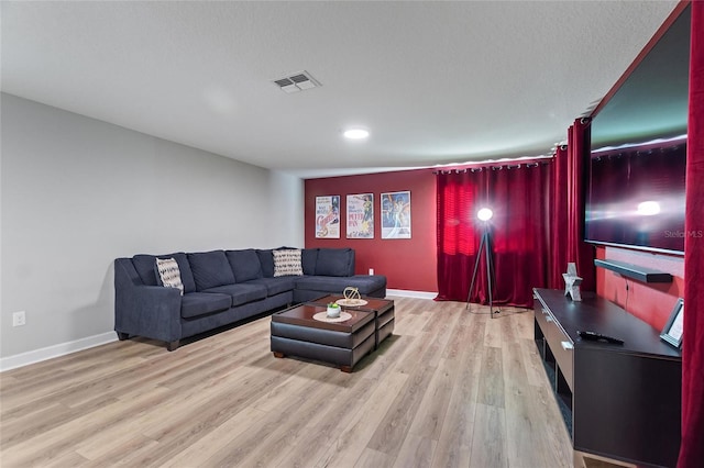 living area with baseboards, visible vents, and wood finished floors