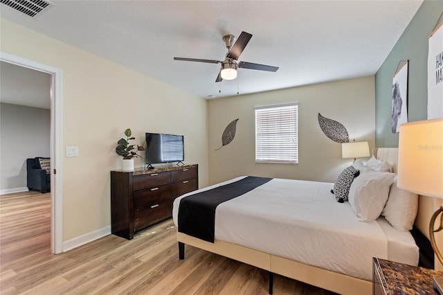 bedroom featuring baseboards, light wood-style flooring, visible vents, and ceiling fan