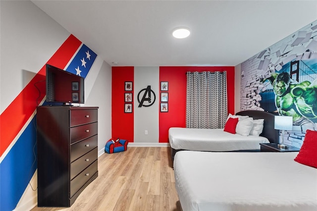 bedroom featuring light wood-style flooring, baseboards, and an accent wall