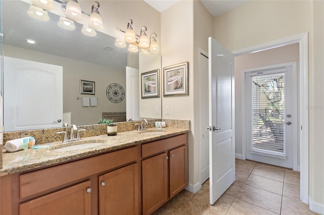 bathroom featuring tile patterned floors, a sink, double vanity, and baseboards