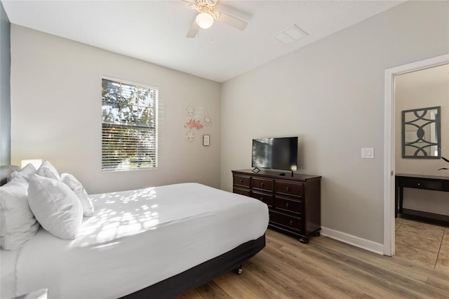 bedroom with baseboards, visible vents, wood finished floors, and a ceiling fan