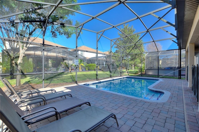 pool with glass enclosure, a lawn, and a patio area