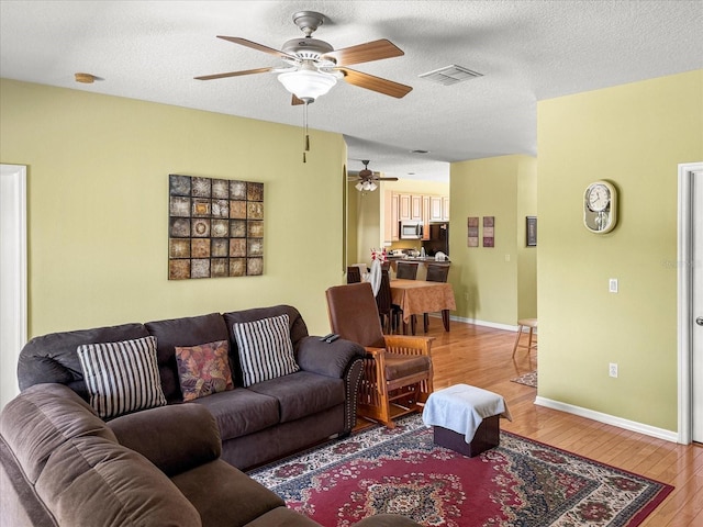 7733 Beridale Ct, Orlando, FL 32818 - living room with a ceiling fan, light wood finished floors, a textured ceiling, baseboards, and visible vents