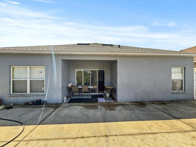 7733 Beridale Ct, Orlando, FL 32818 - rear view of property with stucco siding, a shingled roof, and a patio area