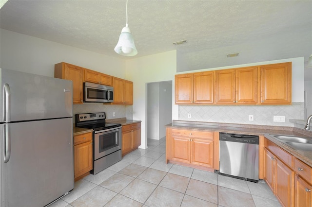 554 NW Twylite Ter, Port St Lucie, FL 34983 - kitchen featuring appliances with stainless steel finishes, a sink, tasteful backsplash, light tile patterned floors, and hanging light fixtures