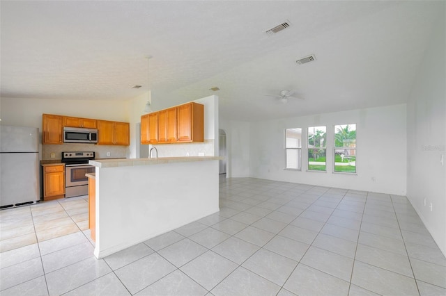 554 NW Twylite Ter, Port St Lucie, FL 34983 - kitchen featuring stainless steel appliances, open floor plan, lofted ceiling, light countertops, and light tile patterned flooring