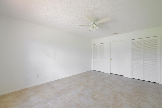 554 NW Twylite Ter, Port St Lucie, FL 34983 - unfurnished bedroom featuring multiple closets, a textured ceiling, baseboards, and ceiling fan