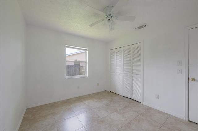 554 NW Twylite Ter, Port St Lucie, FL 34983 - unfurnished bedroom featuring baseboards, light tile patterned floors, a closet, ceiling fan, and a textured ceiling