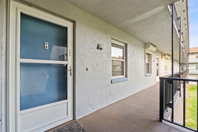 doorway to property featuring stucco siding, a wall mounted air conditioner, and a balcony