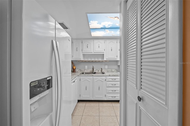 kitchen with white cabinetry, a sink, white fridge with ice dispenser, and light tile patterned flooring