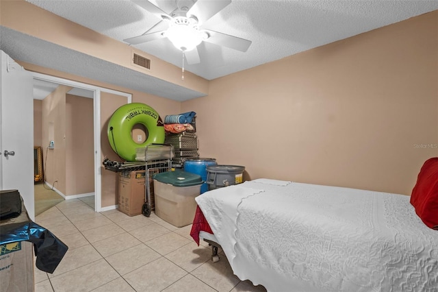 bedroom featuring light tile patterned floors, baseboards, a textured ceiling, visible vents, and a ceiling fan