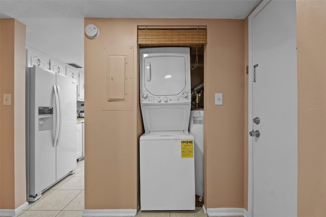 washroom with light tile patterned floors, baseboards, stacked washer and dryer, laundry area, and electric panel