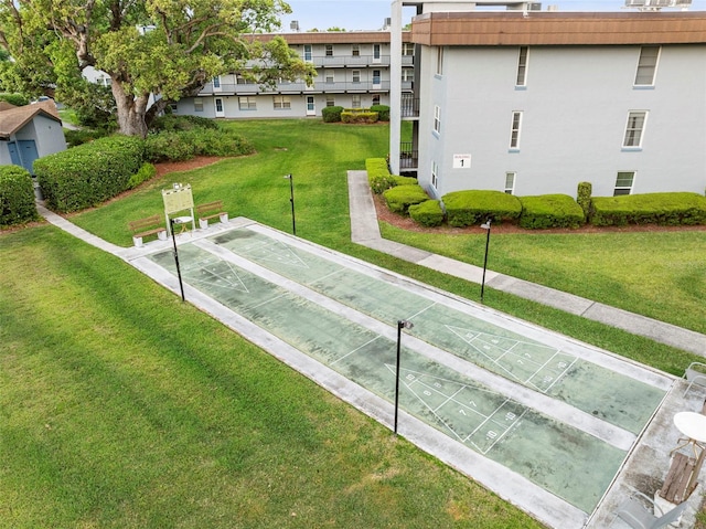 view of home's community featuring shuffleboard and a yard