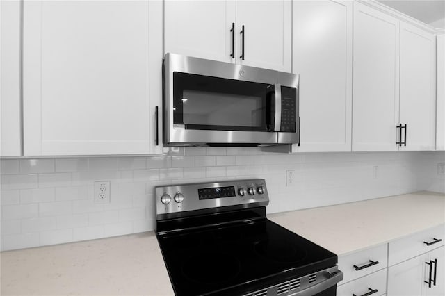 4083 Bannock Ave, Tavares, FL 32778 - kitchen featuring stainless steel appliances, white cabinets, decorative backsplash, and light stone counters