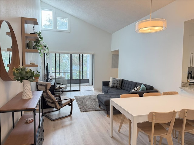 living area with a wealth of natural light, high vaulted ceiling, and light wood finished floors