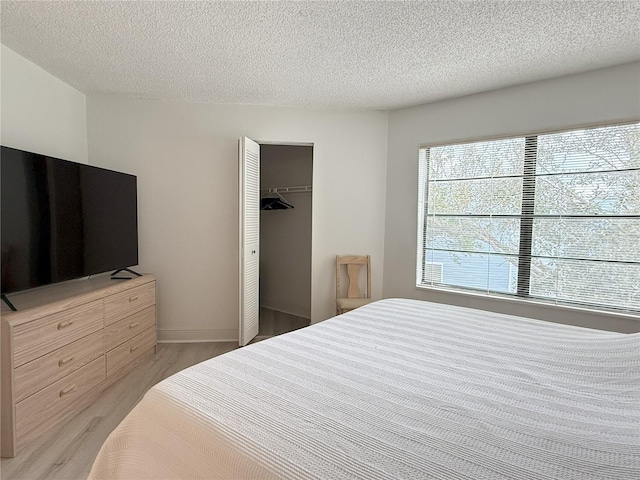 bedroom with light wood-style floors and a textured ceiling