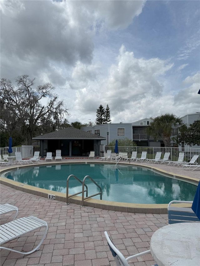 community pool with a patio and fence