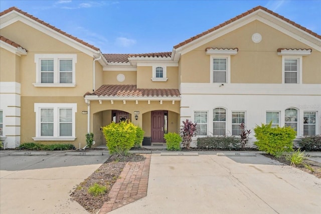 mediterranean / spanish-style home featuring uncovered parking, stucco siding, and a tiled roof