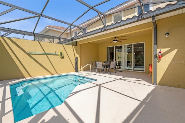 view of swimming pool with a ceiling fan, outdoor dining area, glass enclosure, and a patio