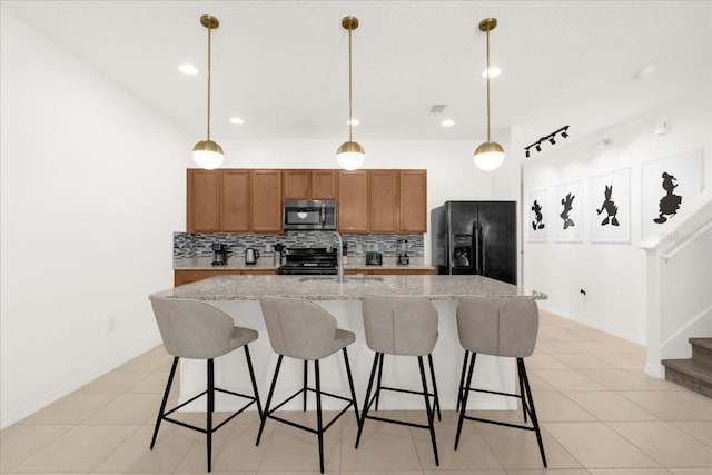 kitchen with stainless steel microwave, black fridge with ice dispenser, stove, and decorative backsplash