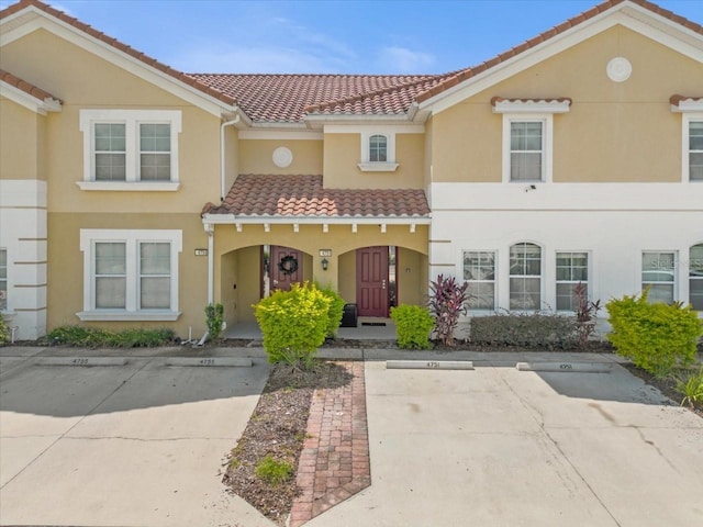 view of front of property with a tile roof, stucco siding, and uncovered parking