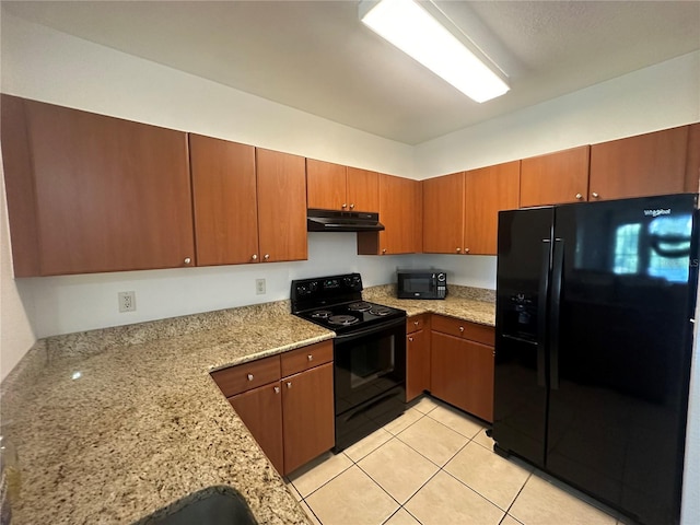 304 E S St Unit 5020, Orlando, FL 32801 - kitchen with light tile patterned floors, under cabinet range hood, light stone counters, black appliances, and brown cabinets