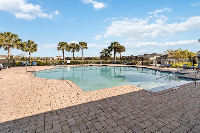 pool with fence, a patio, and a residential view
