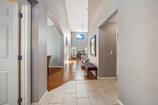 1048 Lake Berkley Dr, Kissimmee, FL 34746 - entrance foyer with light wood-type flooring, baseboards, a textured wall, stairs, and arched walkways
