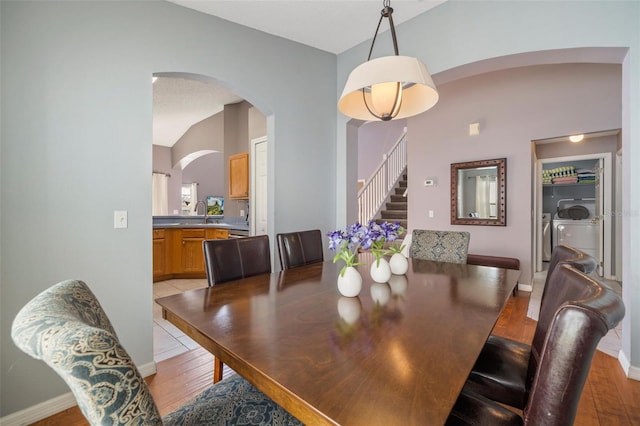 1048 Lake Berkley Dr, Kissimmee, FL 34746 - dining space featuring light wood-style flooring, independent washer and dryer, stairway, and arched walkways