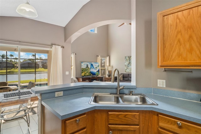 1048 Lake Berkley Dr, Kissimmee, FL 34746 - kitchen with brown cabinetry, arched walkways, a peninsula, vaulted ceiling, and a sink