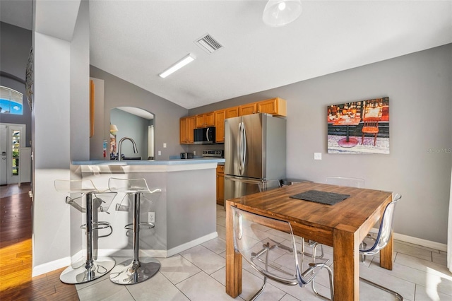 1048 Lake Berkley Dr, Kissimmee, FL 34746 - kitchen featuring light countertops, visible vents, lofted ceiling, stainless steel appliances, and arched walkways